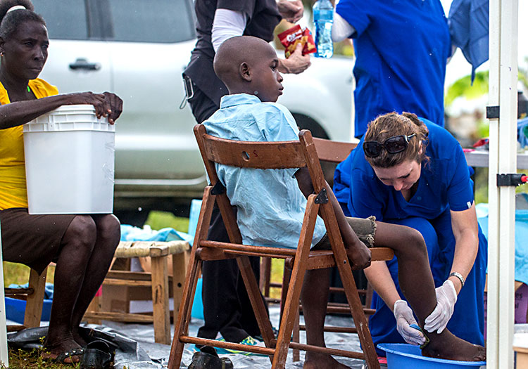 Young Haitian boy receives treatment as mother waites with Disaster Relief Bucket.
