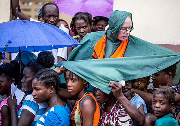 Volunteer covering Haitians from the rain.